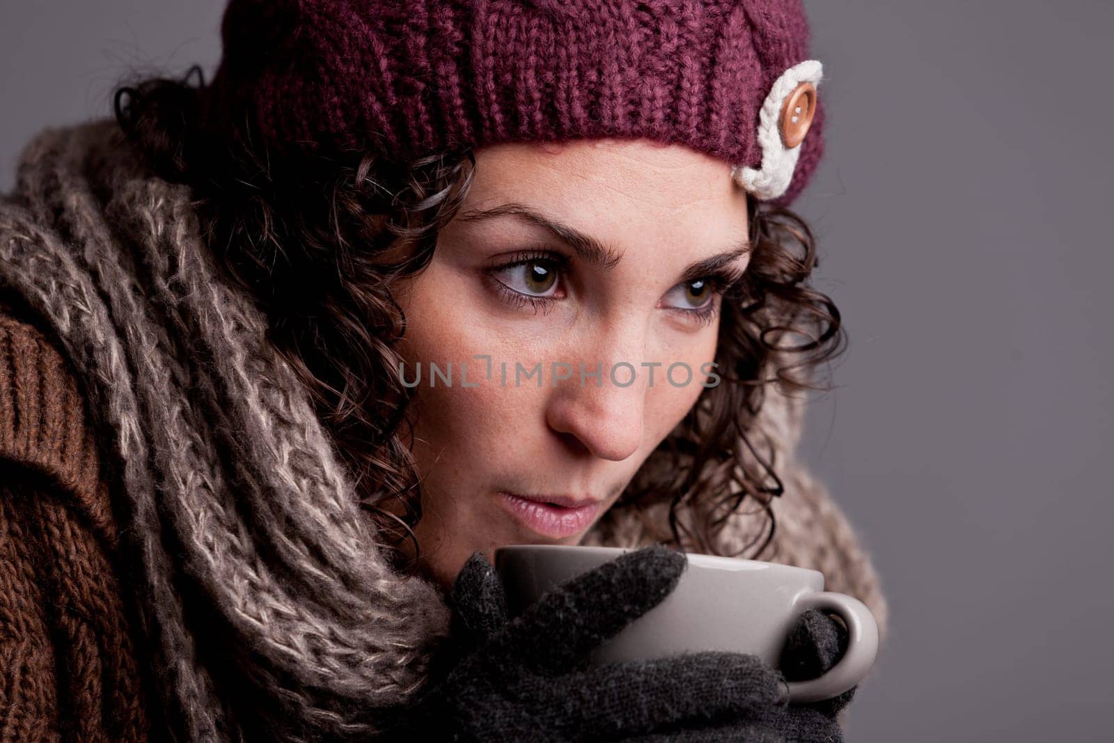 it's winter and this girl with wool hat and scarf drinks a hot chocolate or hot tea or milk from a big mug and she's happy
