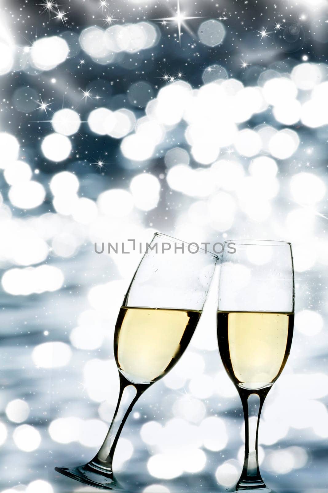 Glasses with champagne against holiday lights and clock close to midnight
