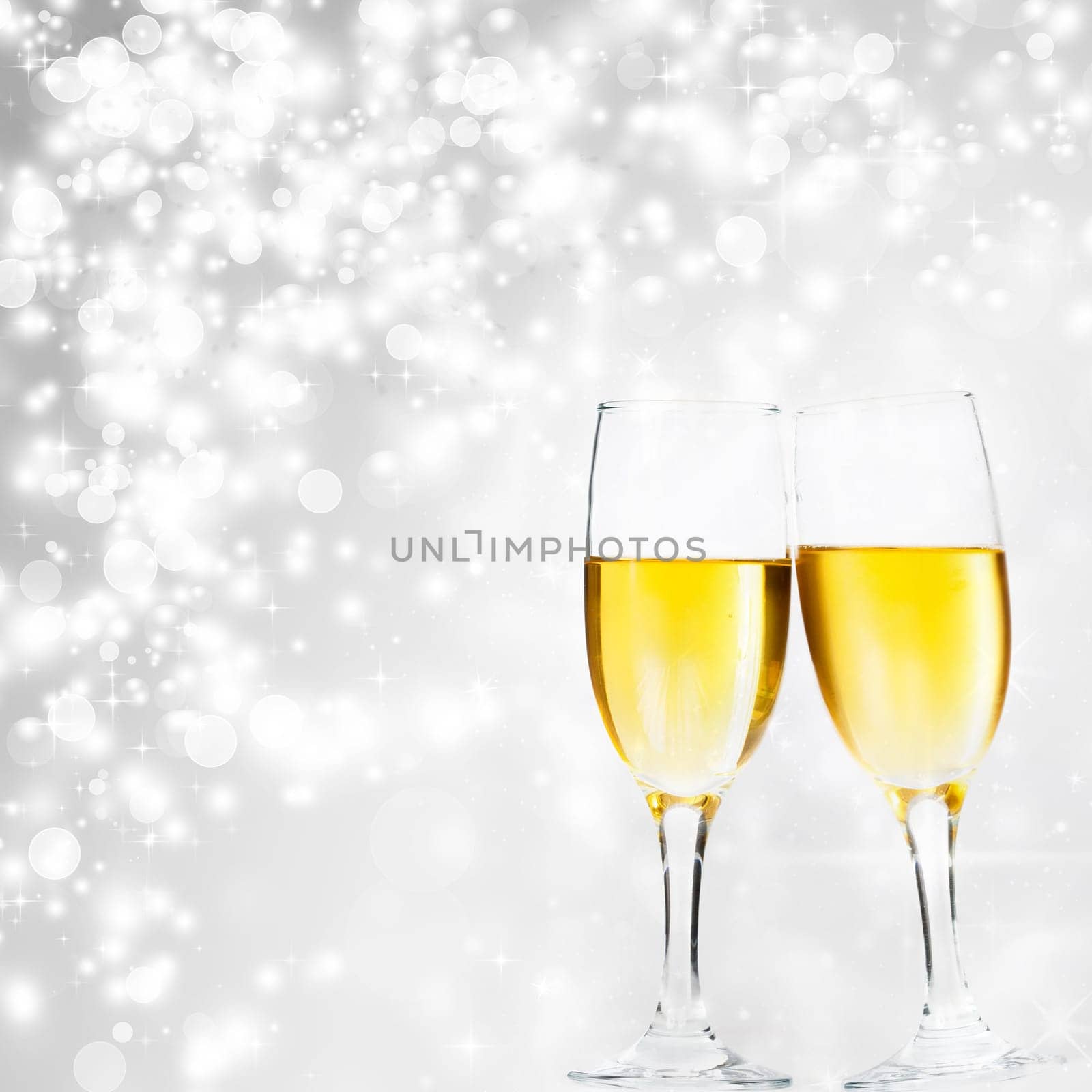 Glasses with champagne against holiday lights and clock close to midnight