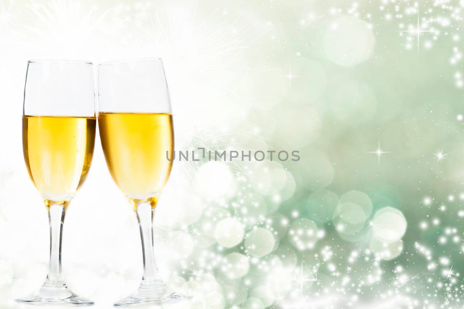 Glasses with champagne against holiday lights and clock close to midnight
