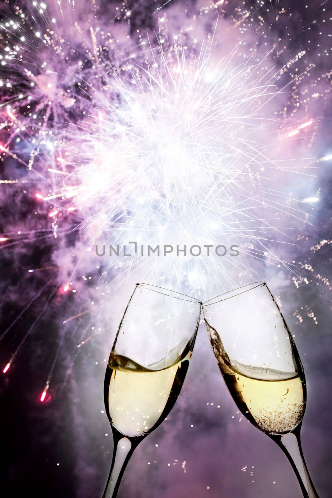 Glasses with champagne against holiday lights and clock close to midnight