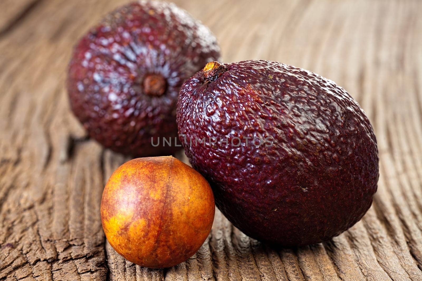 Close up view of two ripe avocados and avocado stone on an old rustic wooden plank