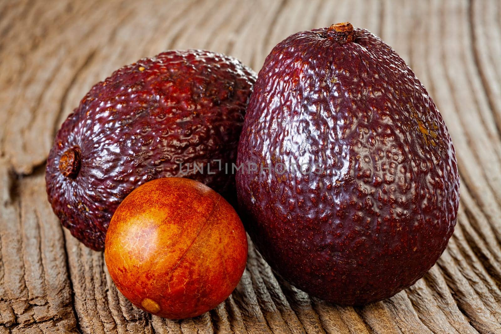 Close up view of two ripe avocados and avocado stone on an old rustic wooden plank