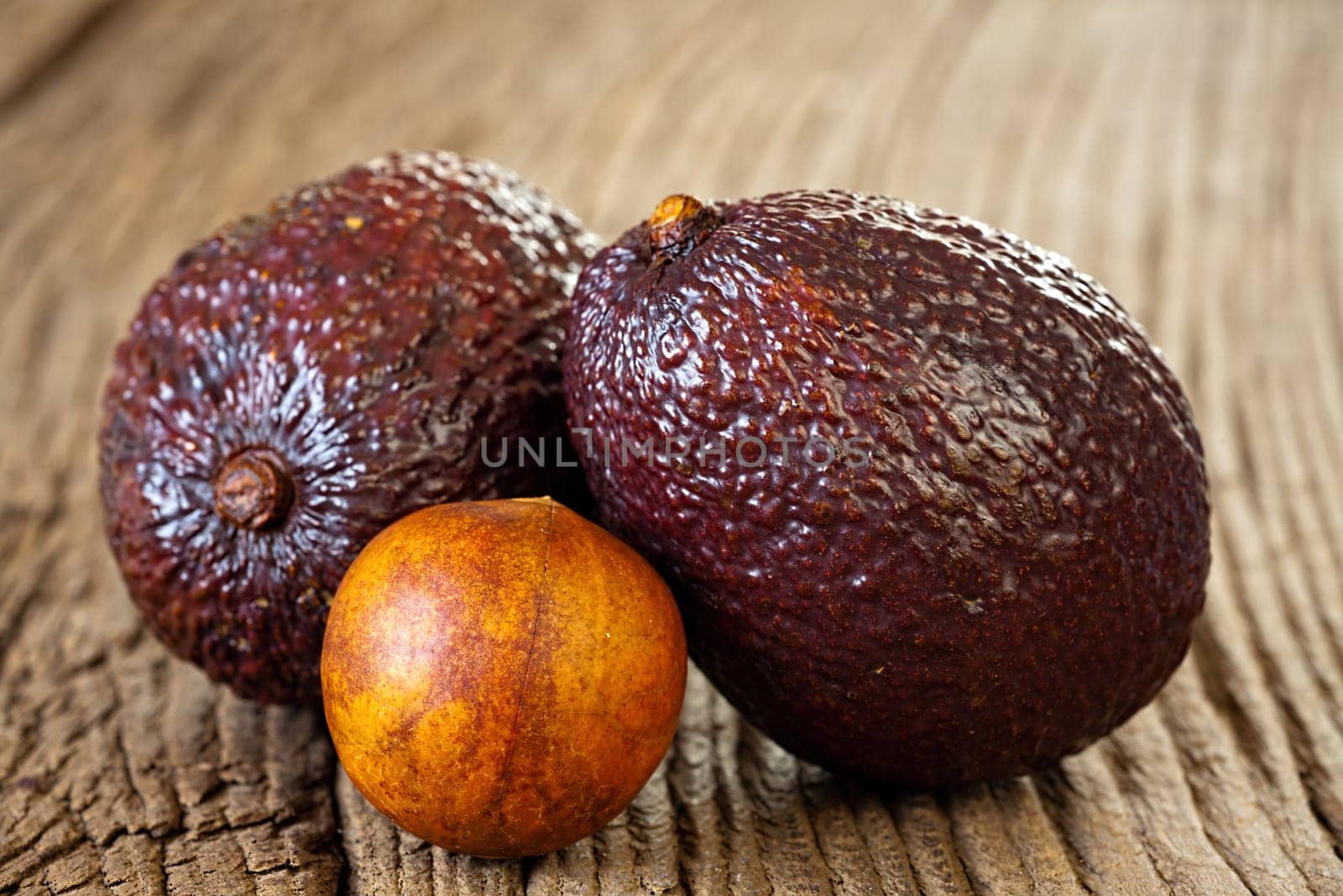 Close up view of two ripe avocados and avocado stone on an old rustic wooden plank