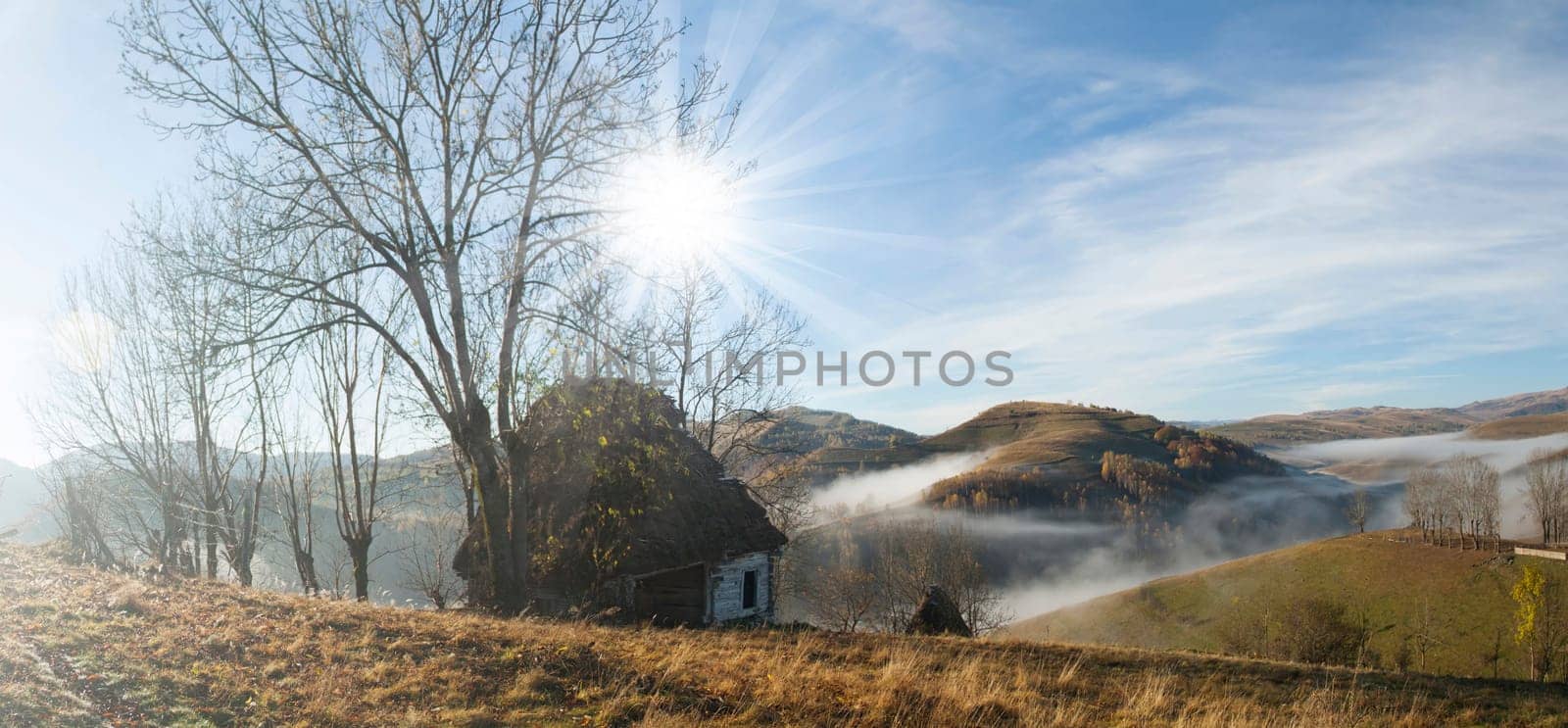 Panoramic view of  Small cottage in the mountains in a foggy autumn morning