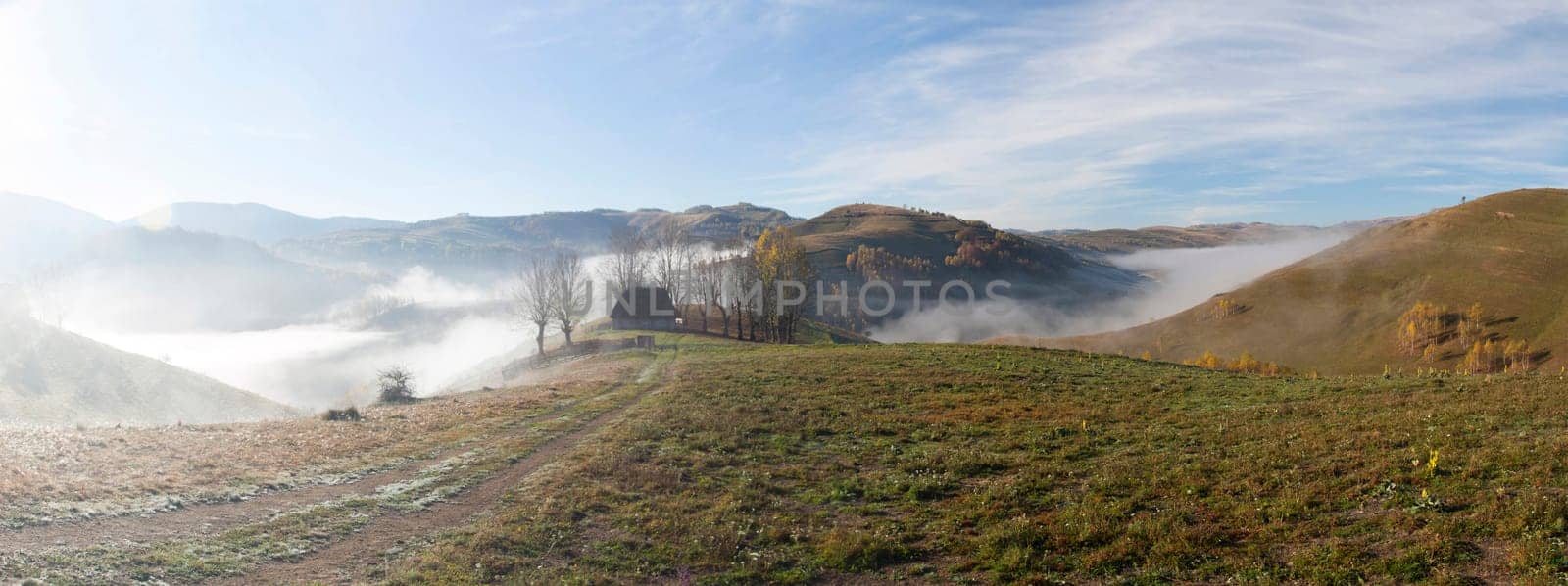 Panoramic view of  Small cottage in the mountains in a foggy autumn morning