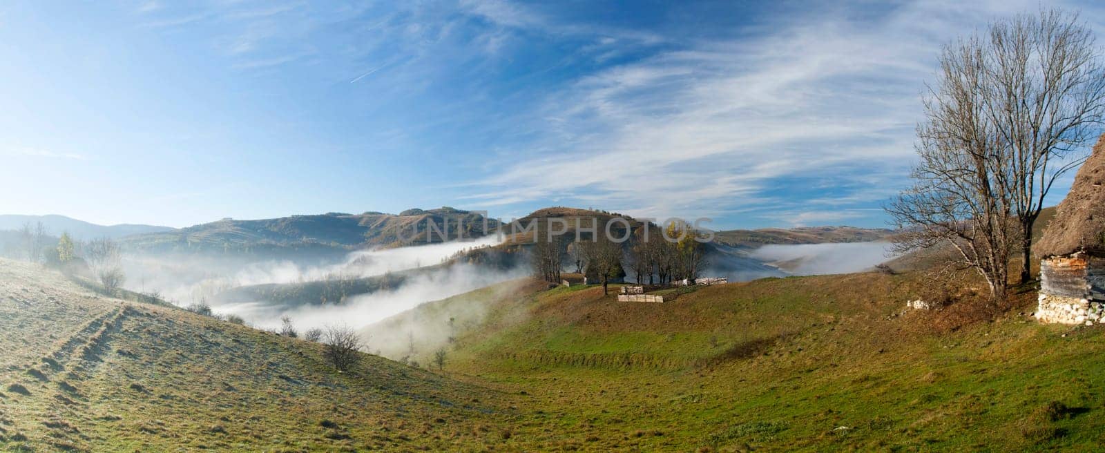 Panoramic view of  Small cottage in the mountains in a foggy autumn morning