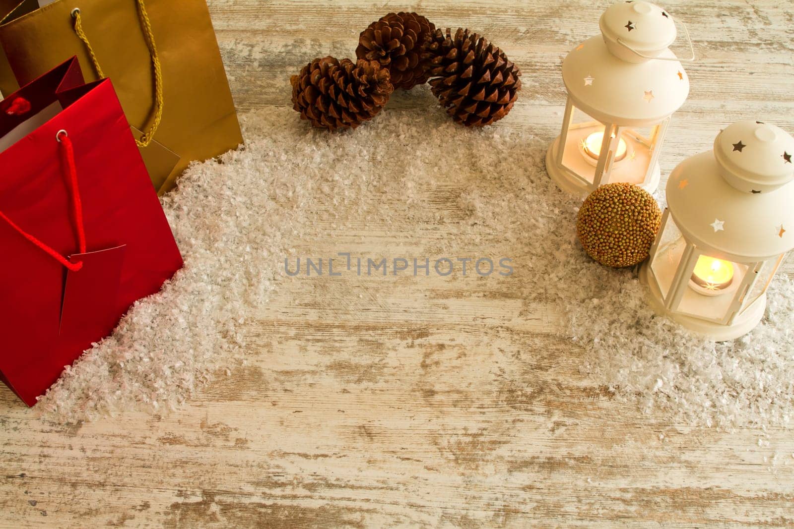 Wooden Christmas background with candles, pine cones, shopping bags and baubles..
