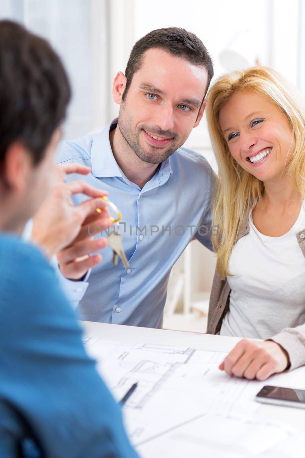 View of a Real estate handing over keys to couple