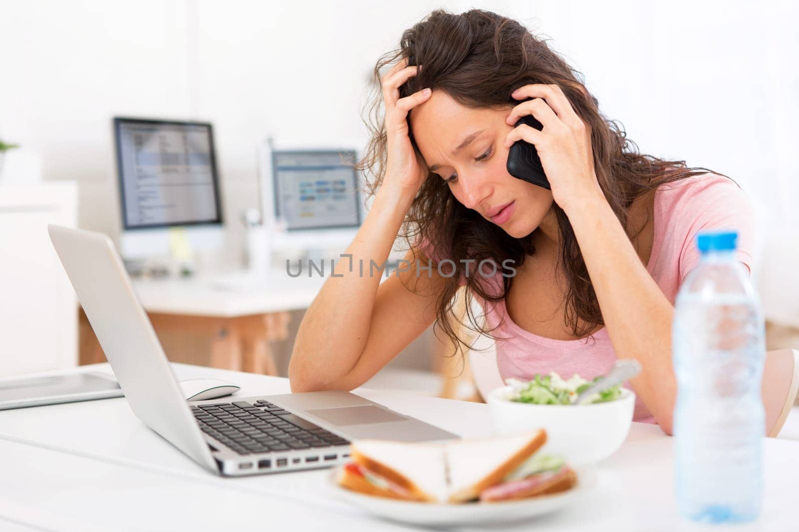 View of a Young attractive student eating salad while phoning