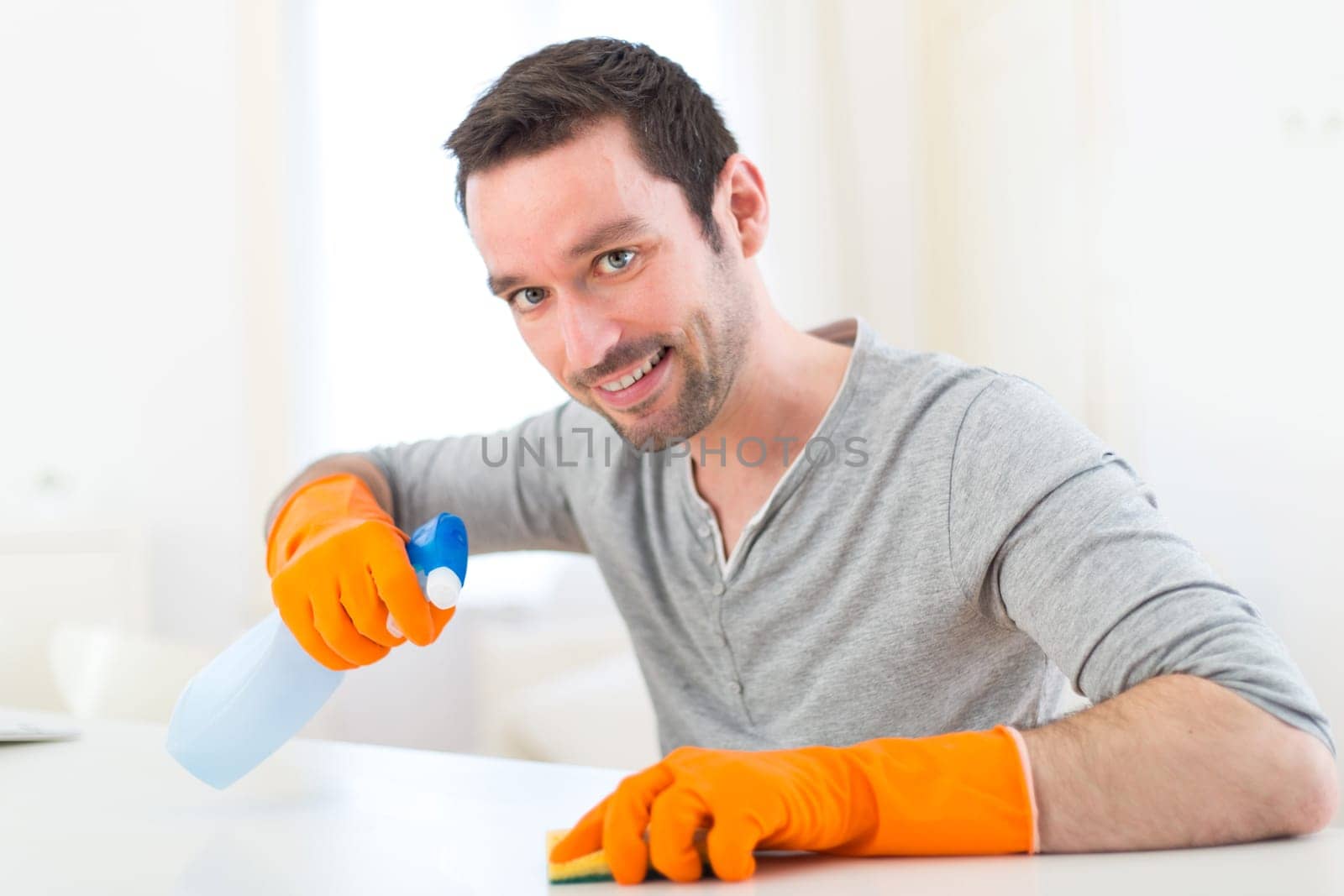 View of a Young attractive man cleaning his flat