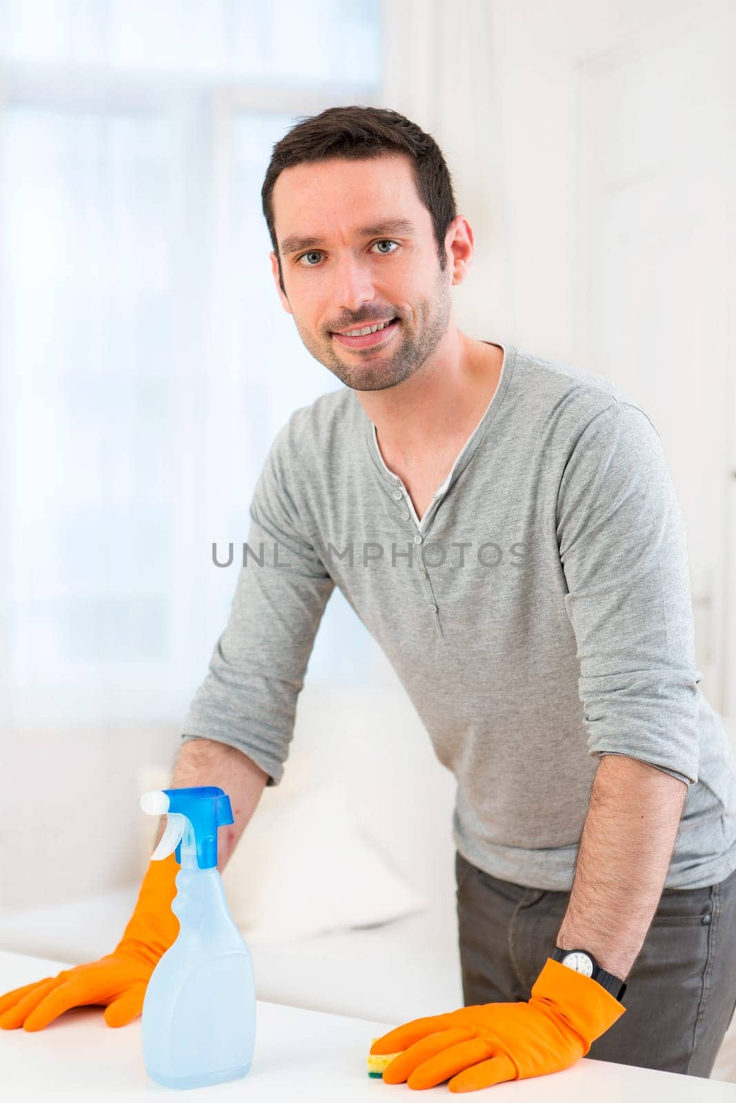 View of a Young attractive man cleaning his flat