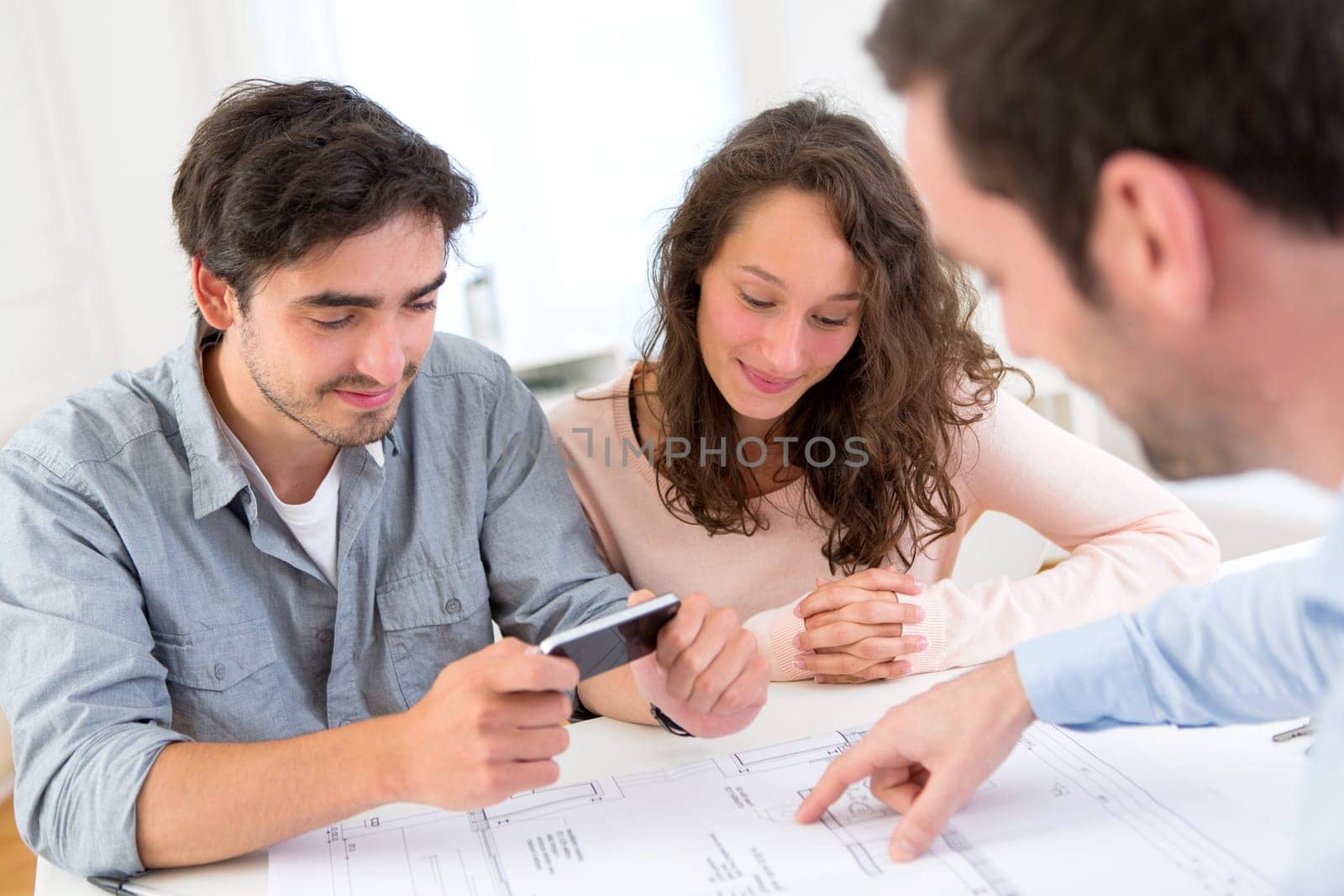 View of a Young attractive man taking picture of blueprint