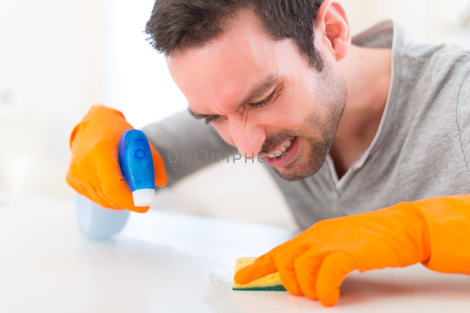 View of a Young attractive man cleaning his flat