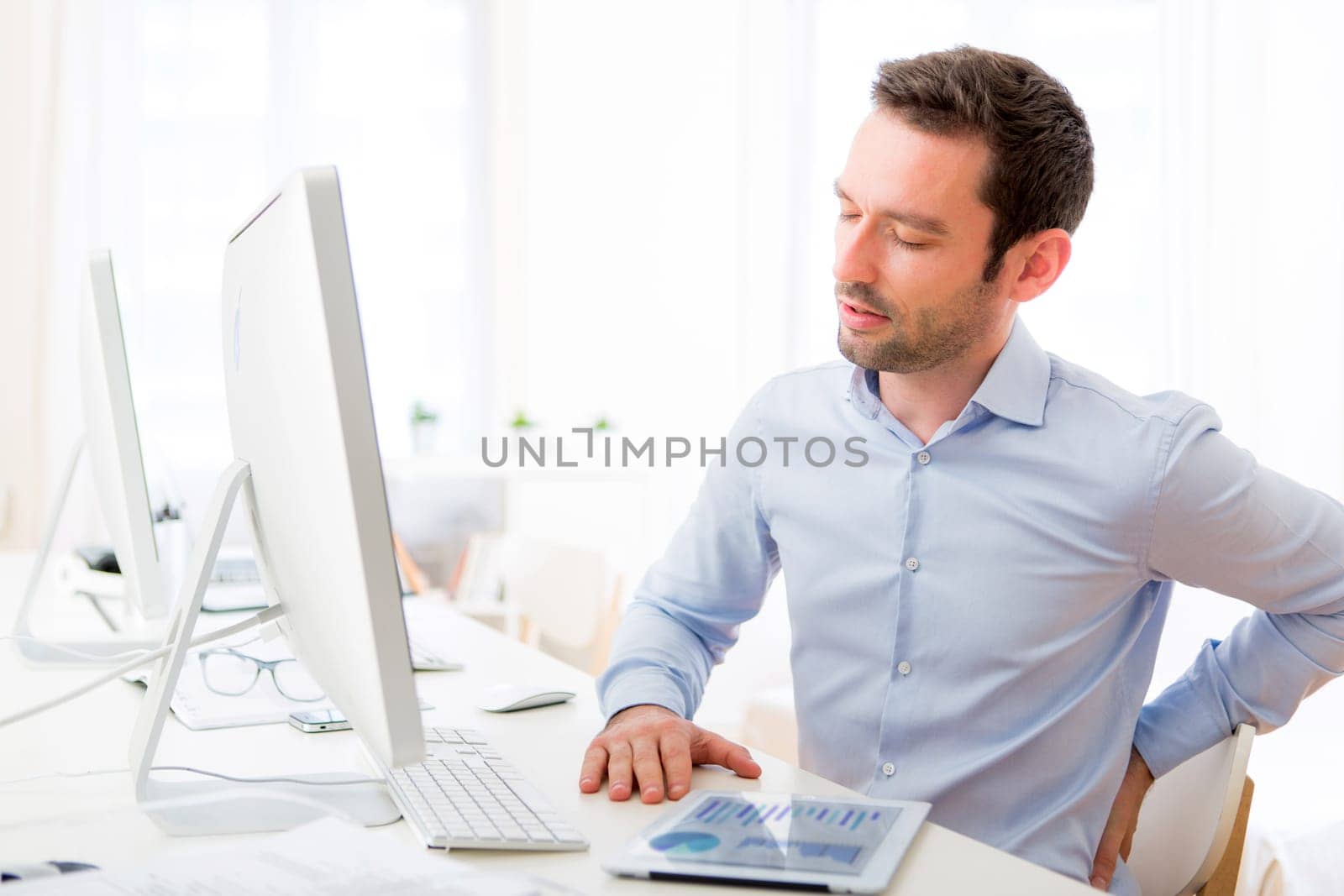 View of a Young attractive man got a back pain at the office