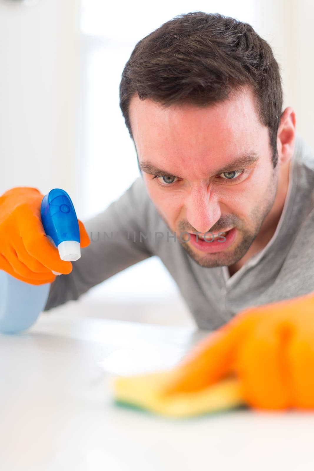 View of a Young attractive man cleaning his flat