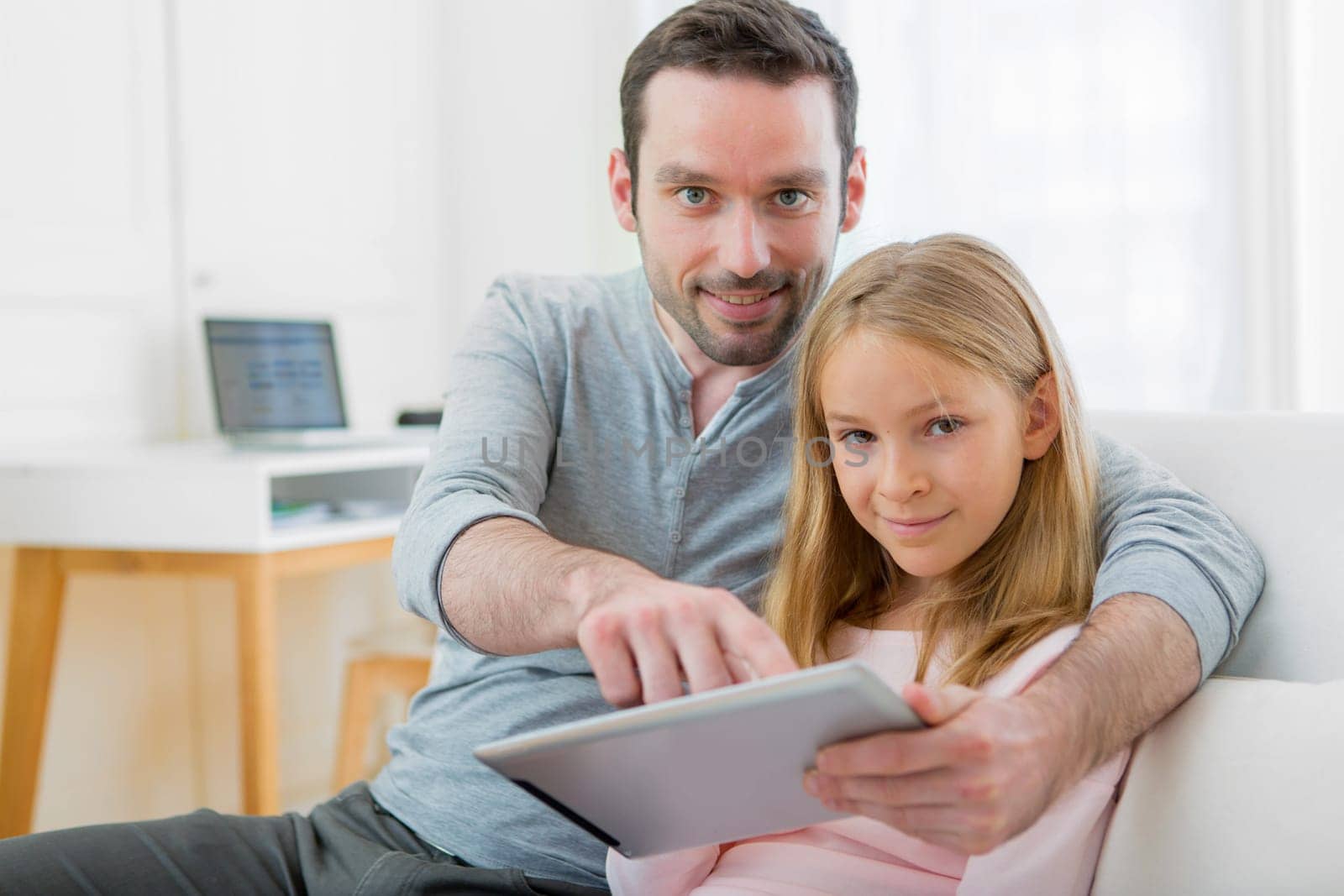 View of a Father and his blond daughter using tablet