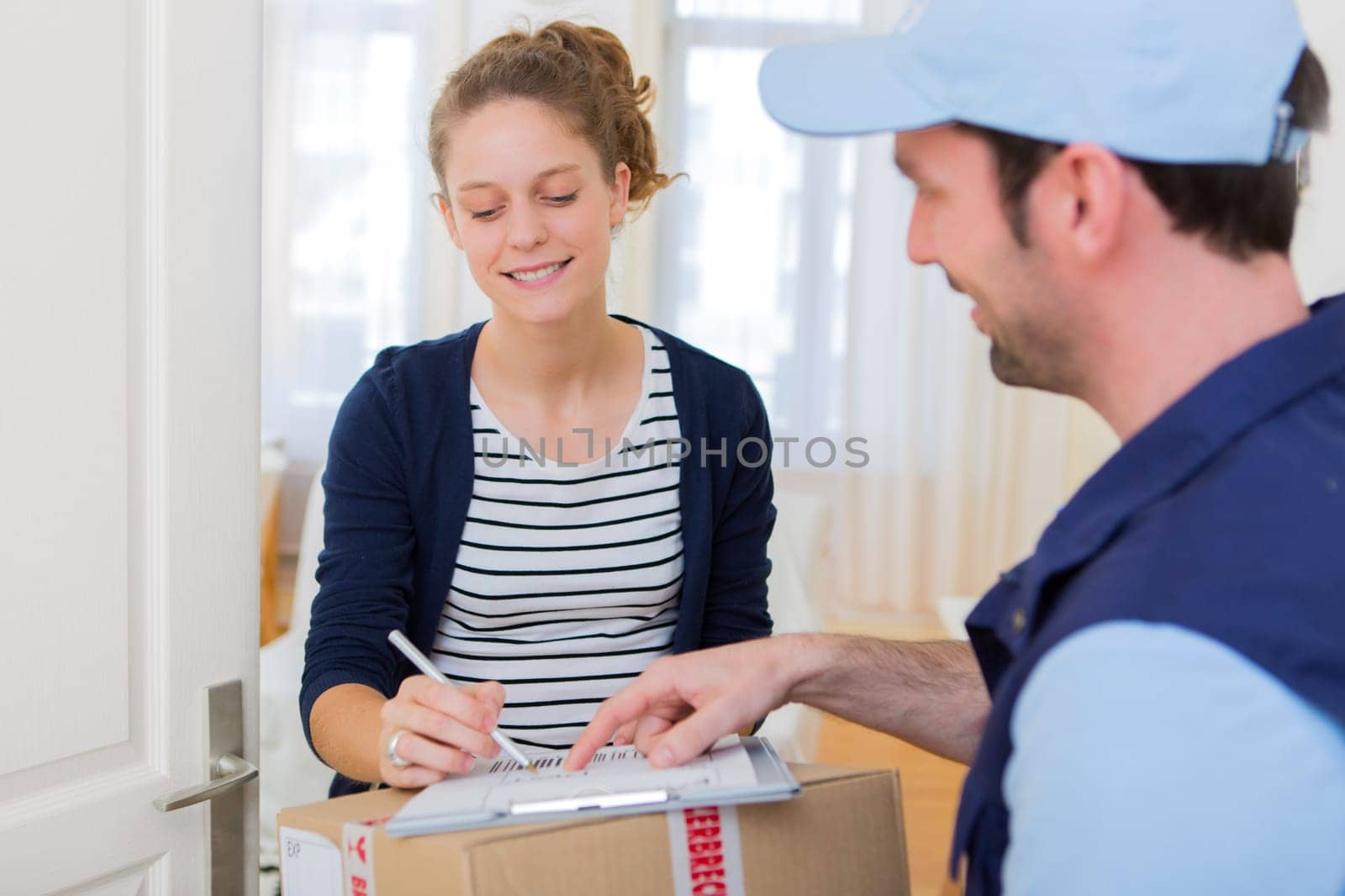 View of a Young attractive woman signing on delivery paper