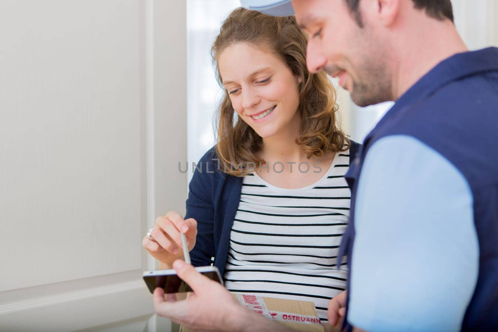 View of a Young attractive woman signing on delivery paper