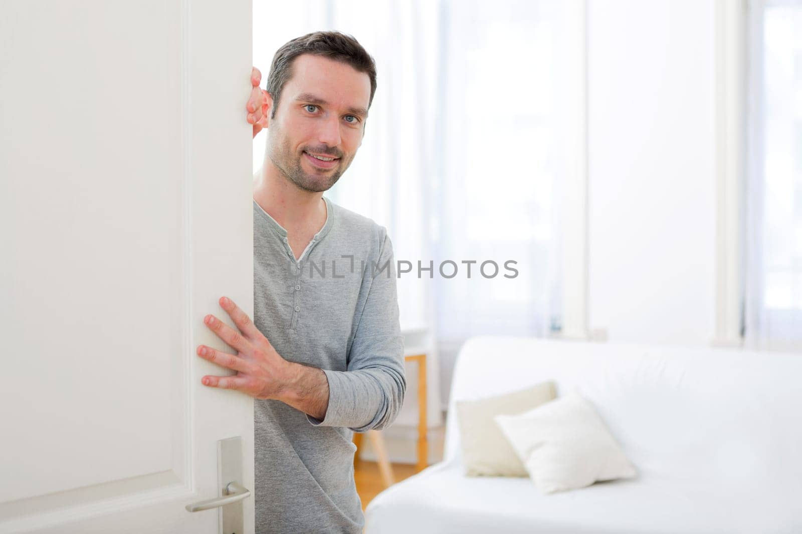 View of a Young attractive man welcoming you in his house