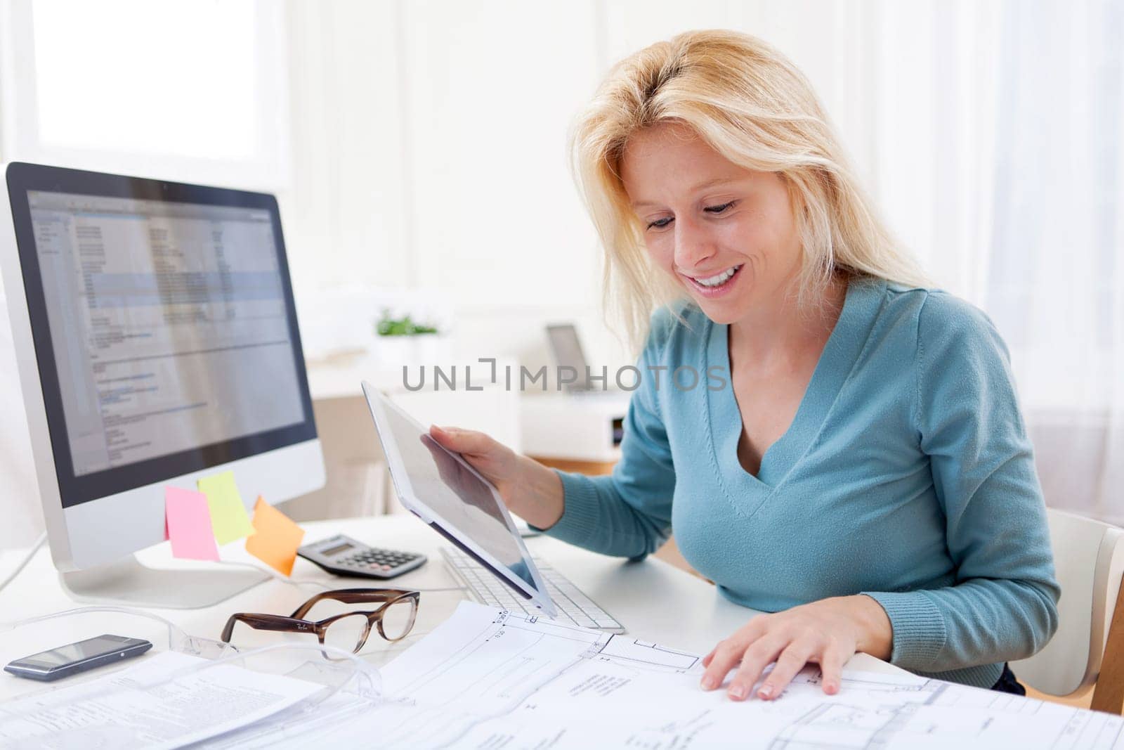 View of a Blonde architect watching blueprint at the office