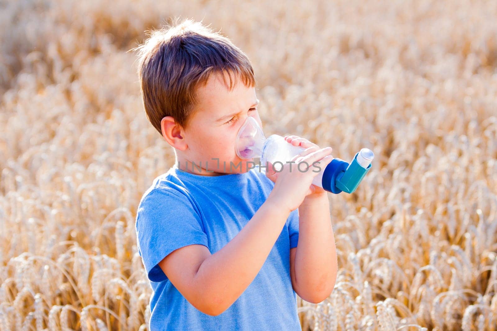 Boy using inhaler for asthma in village with summer sunset