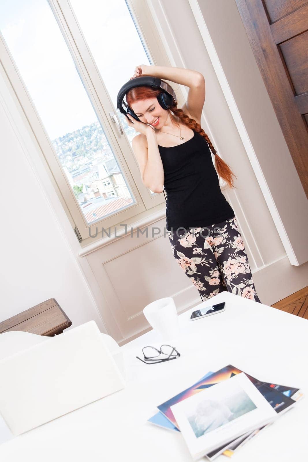 Happy young woman with headphones listening to music in living room