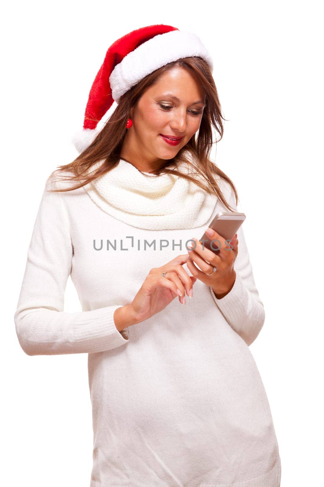Attractive woman with red Santa hat reads a text message on her phone smartphone and sends Christmas wishes smiling with joy isolated on white with text-free free-space