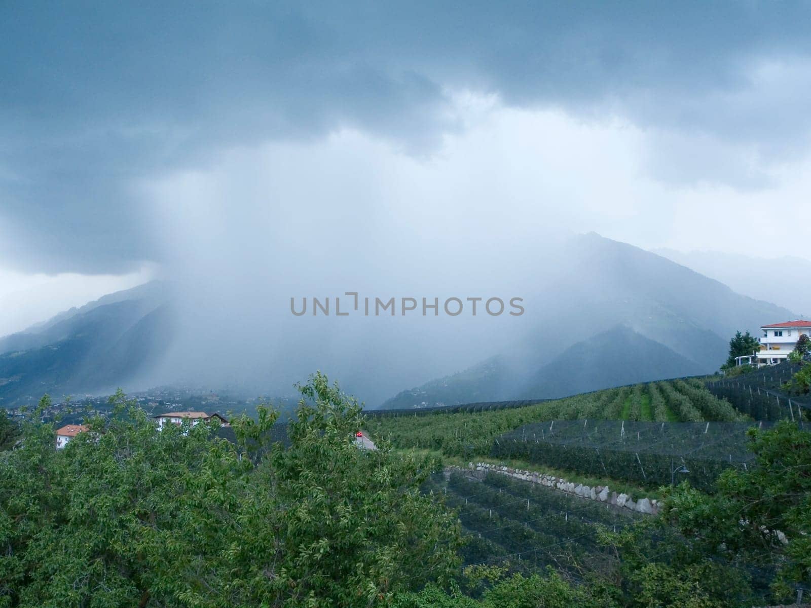 wide-angleview of the Merano valley with a rain cloud above it in summer