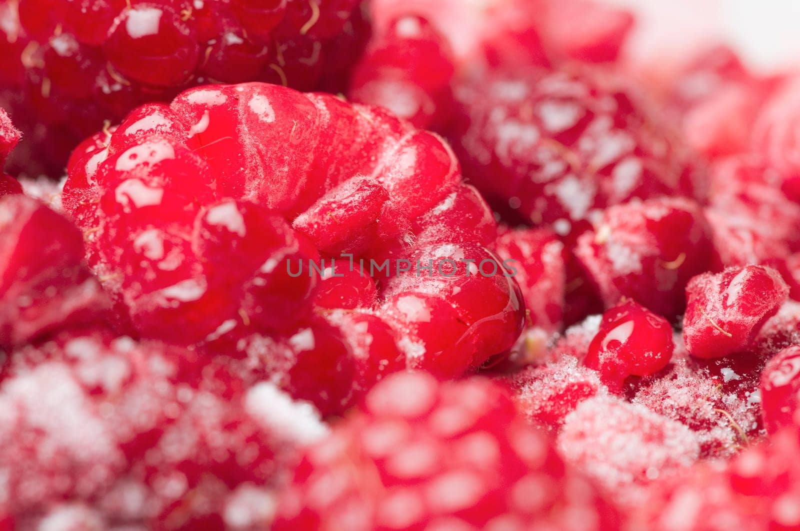 format-filling macro view of thawing raspberries with isolated frost crystals