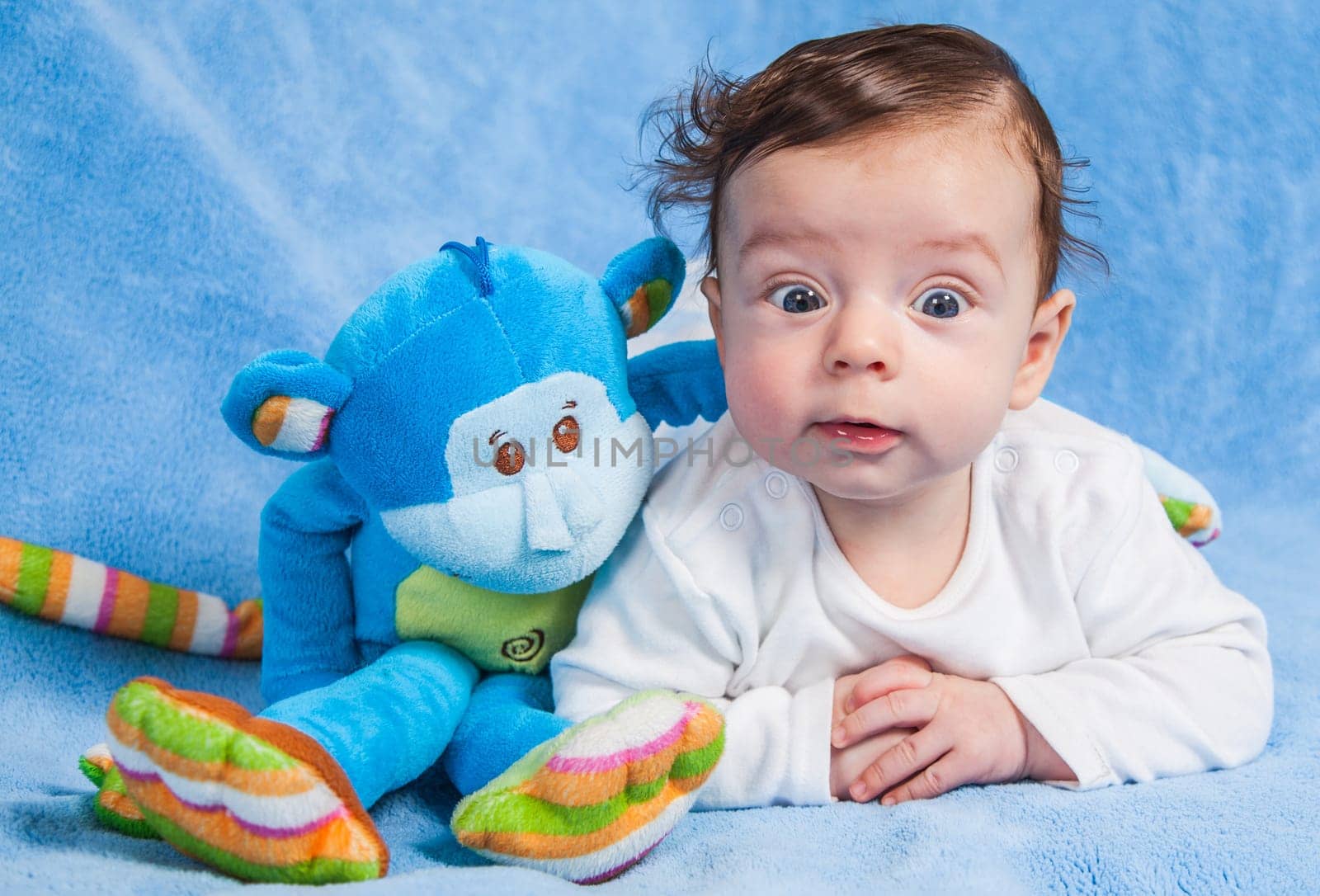Portrait of an adorable smiling baby playing with a monkey toy.