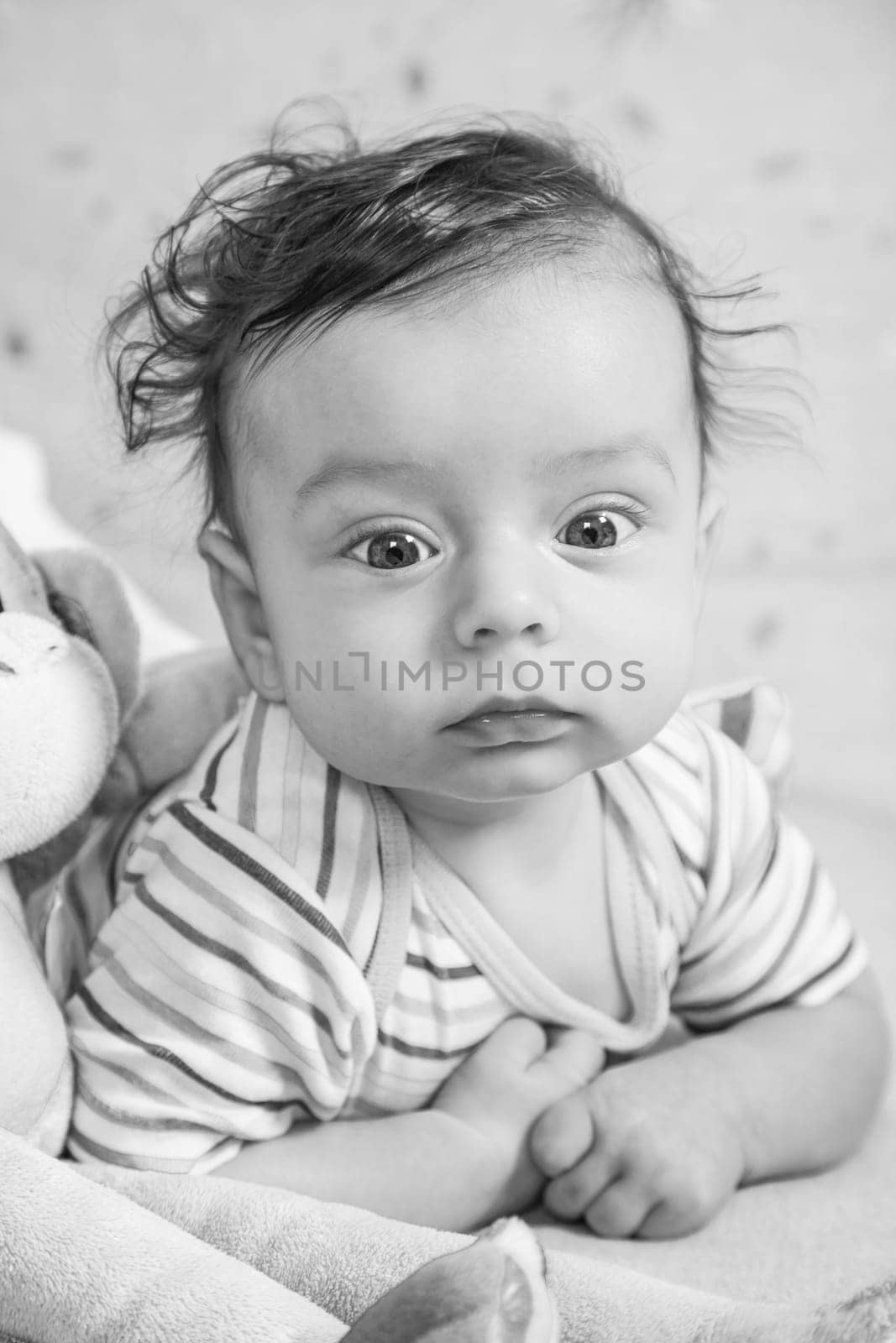Portrait of an adorable smiling baby playing with a monkey toy.