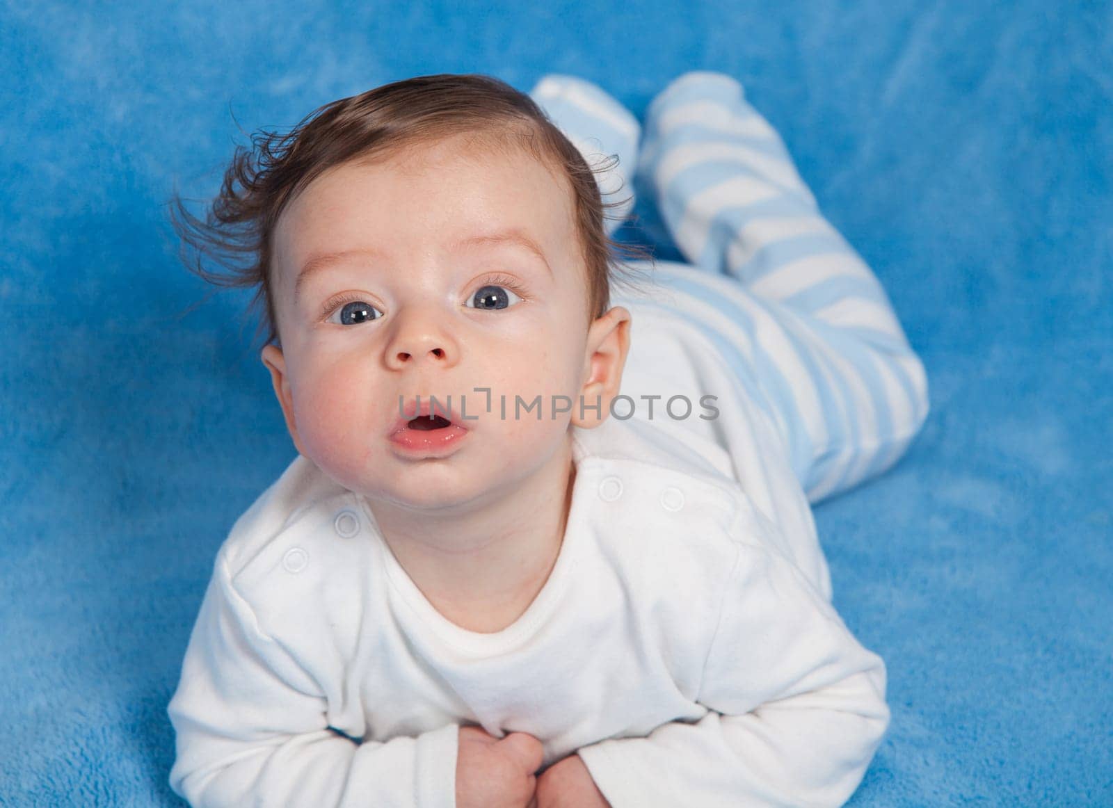 Portrait of an adorable baby boy on a blue blanket.