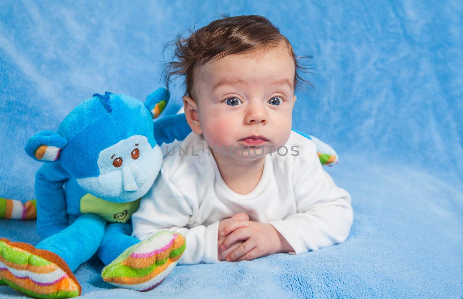 Portrait of an adorable smiling baby playing with a monkey toy.
