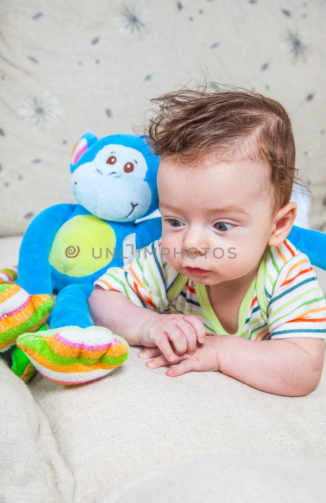 Portrait of an adorable smiling baby playing with a monkey toy.