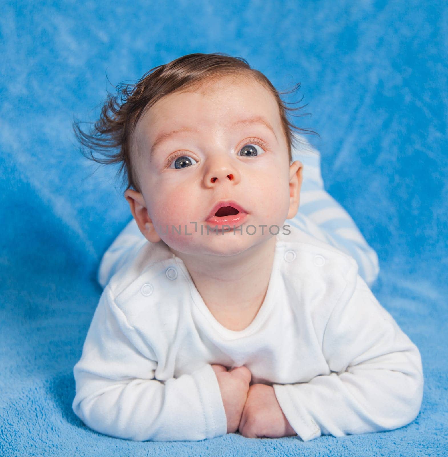 Portrait of an adorable baby boy on a blue blanket.