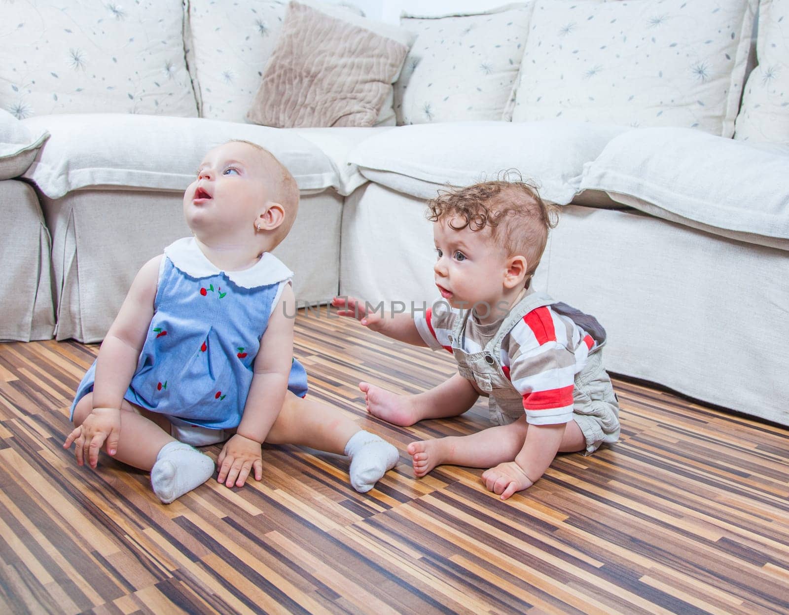 Portrait of baby girl and baby boy playing at home on the floor.