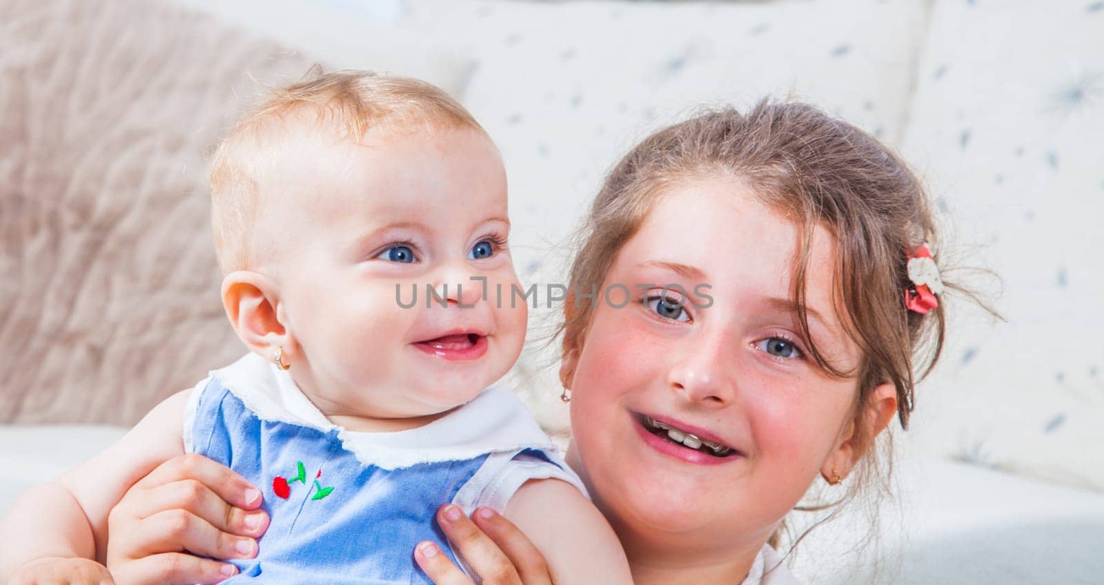 Big sister holding her 1 year old baby sister.