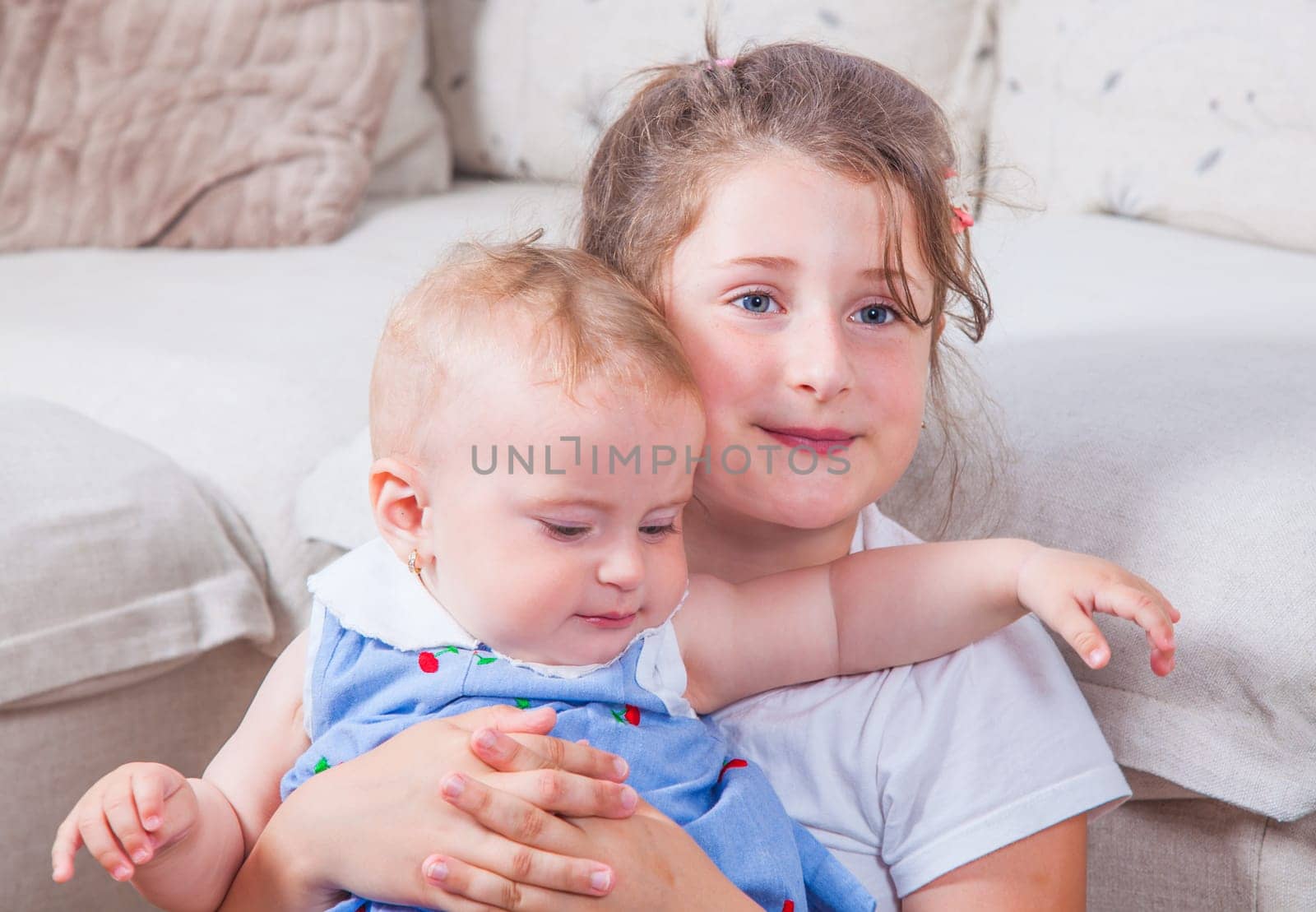 Big sister holding her 1 year old baby sister.