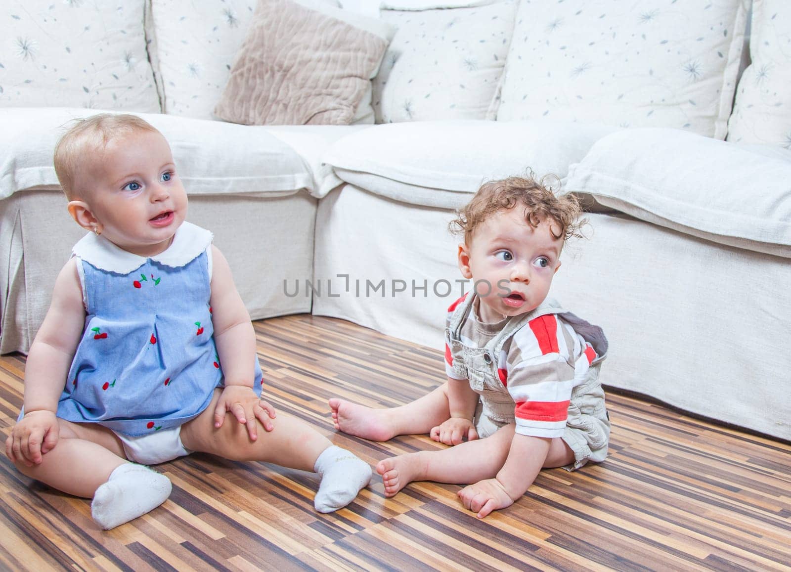 Portrait of baby girl and baby boy playing at home on the floor.
