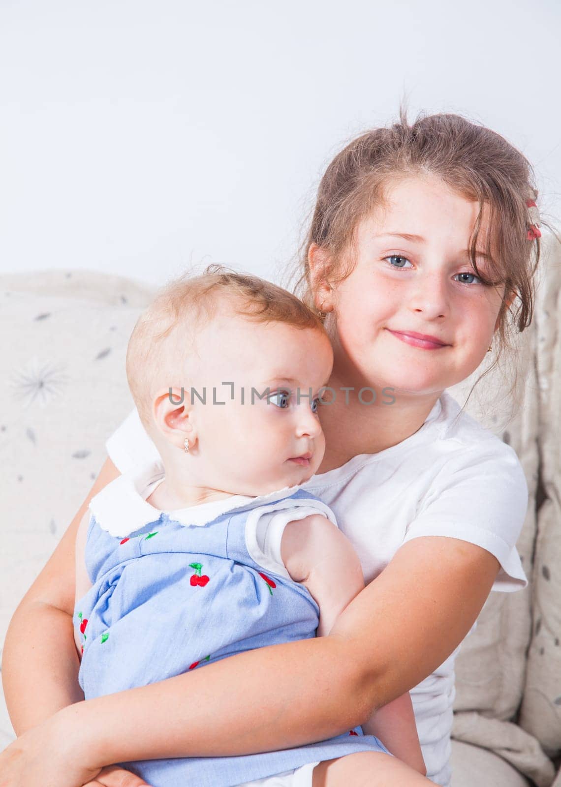 Big sister holding her 1 year old baby sister.