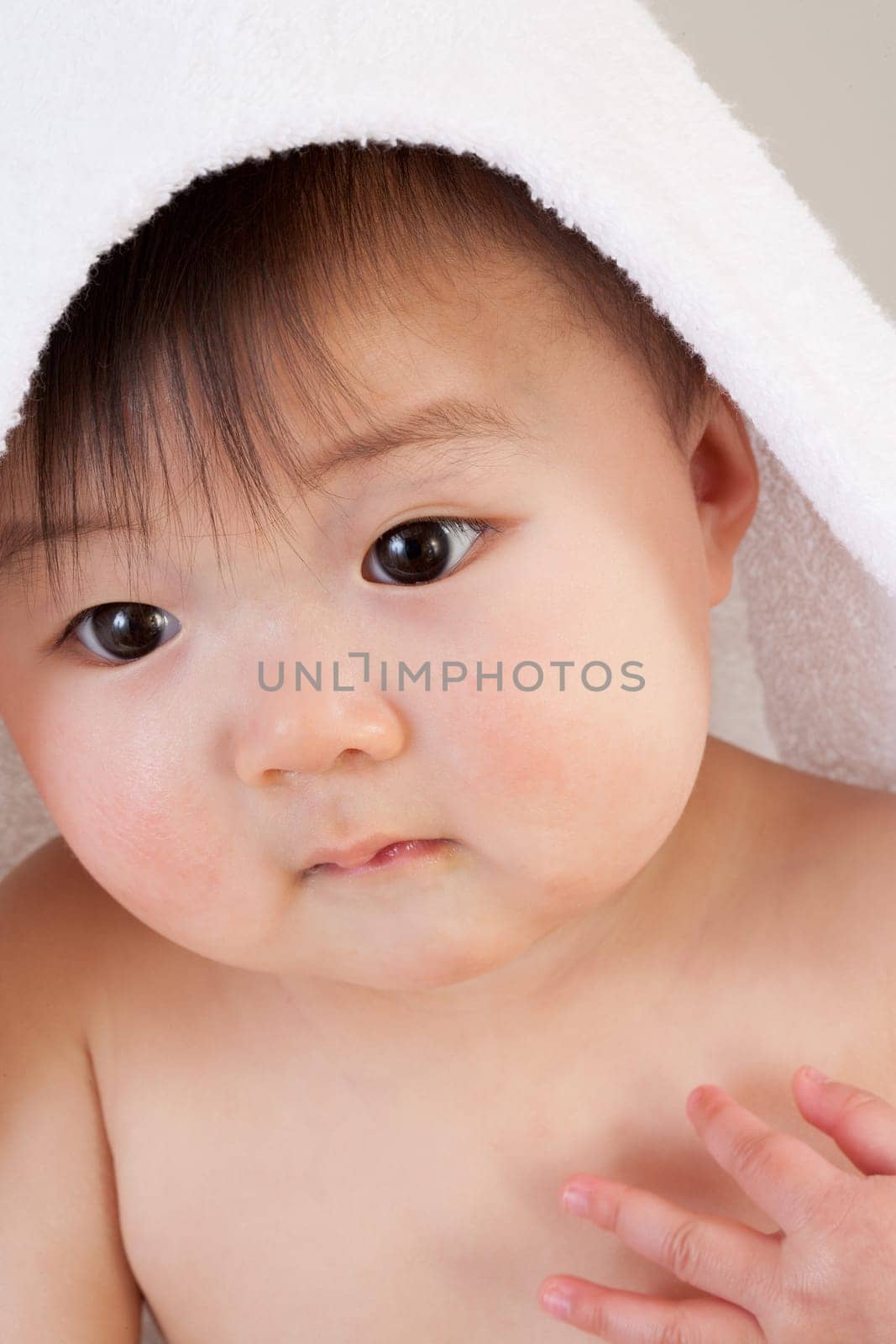 Cute Asian baby sitting with a towel over his head