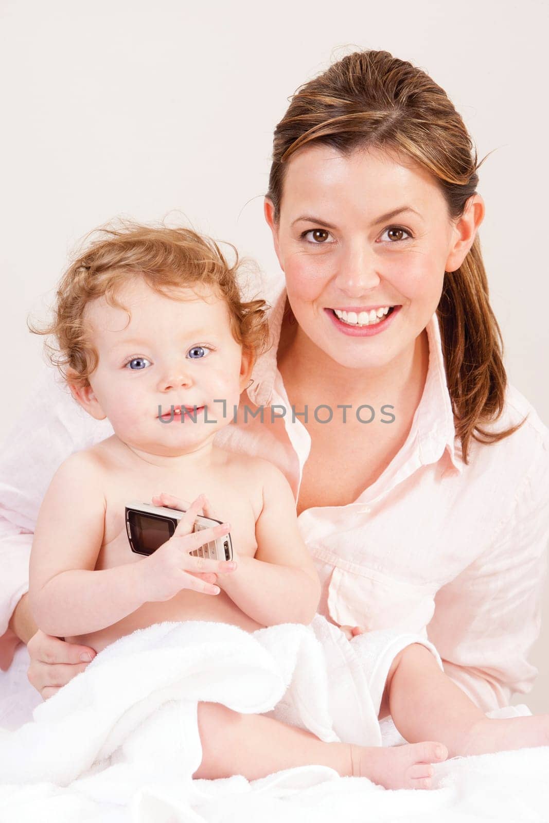 Little girl playing with her mother's phone whilst she gets dried after a bath