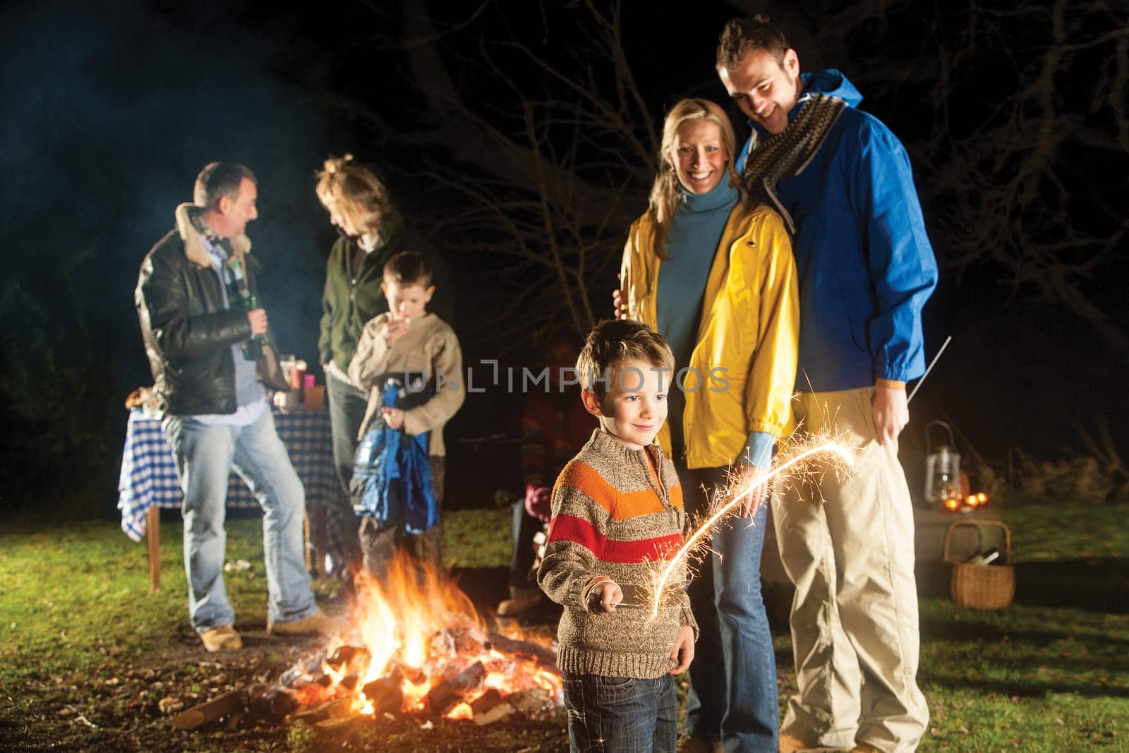 Family in garden enjoying a bonfire and playing with sparklers
