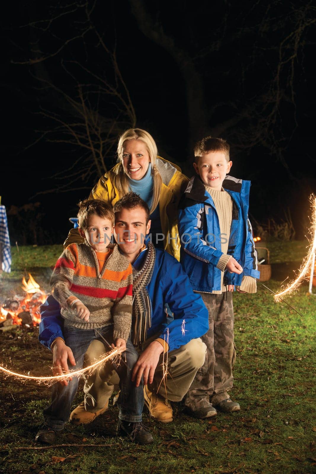 Brothers posing with sparklers on bonfire night with their parents