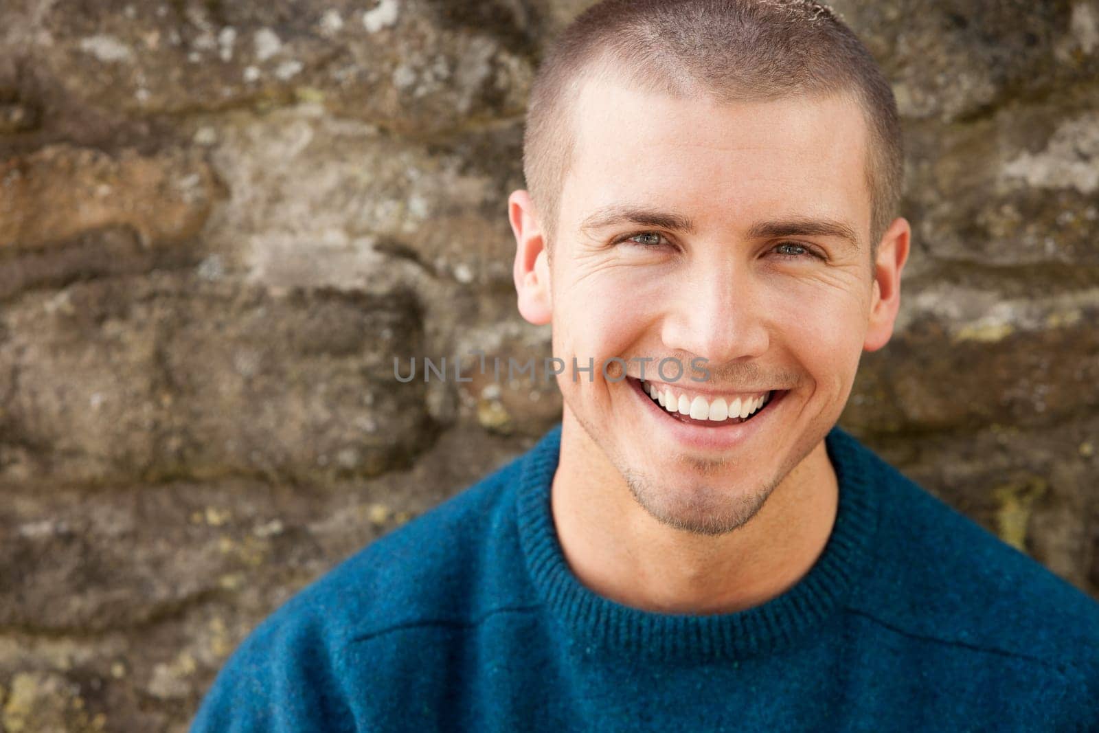 Attractive young man sitting outside. He is smiling at the camera.