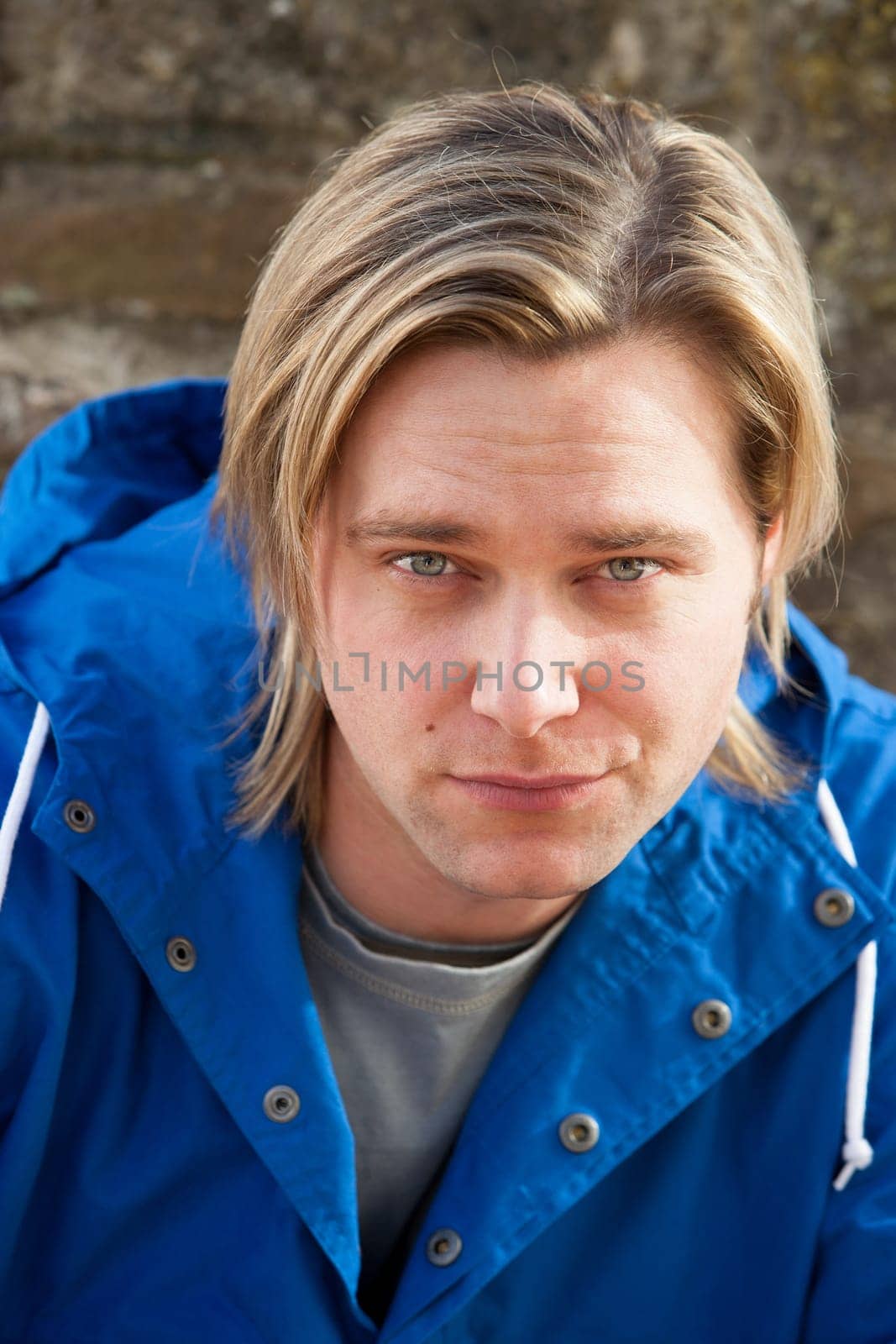 Attractive young man sitting outside. He is looking pensively at the camera.