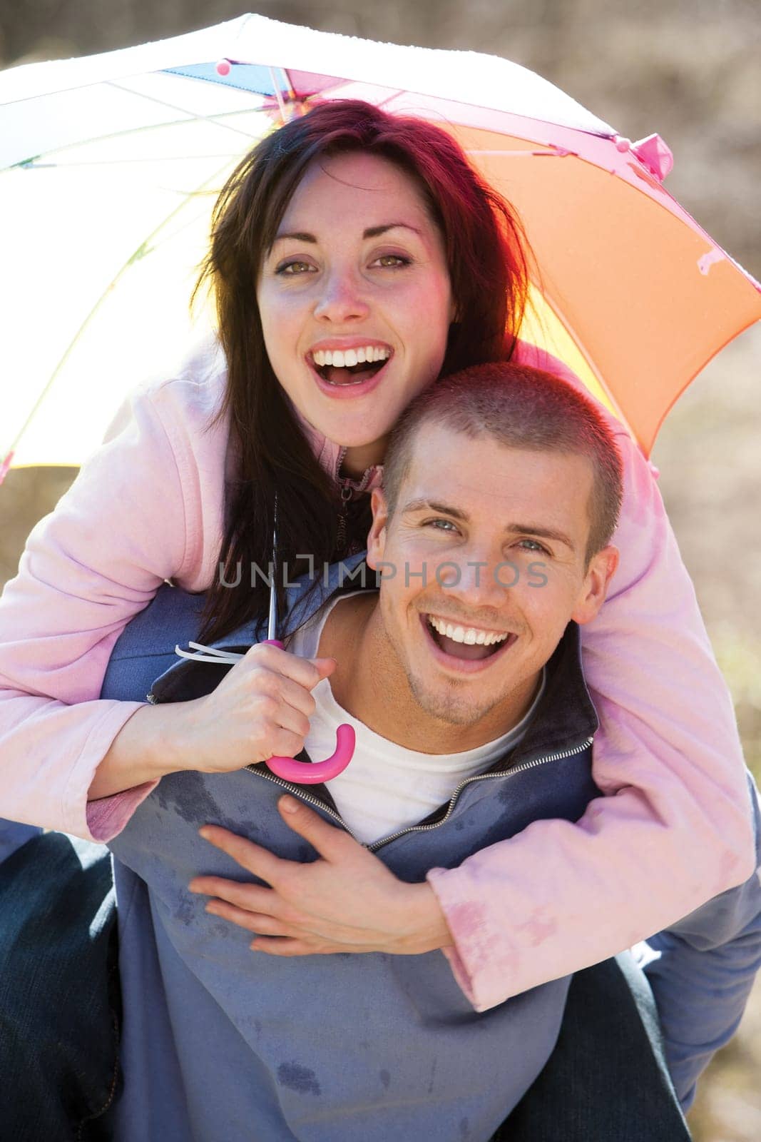 Young couple laughing in the rain under an umbrella