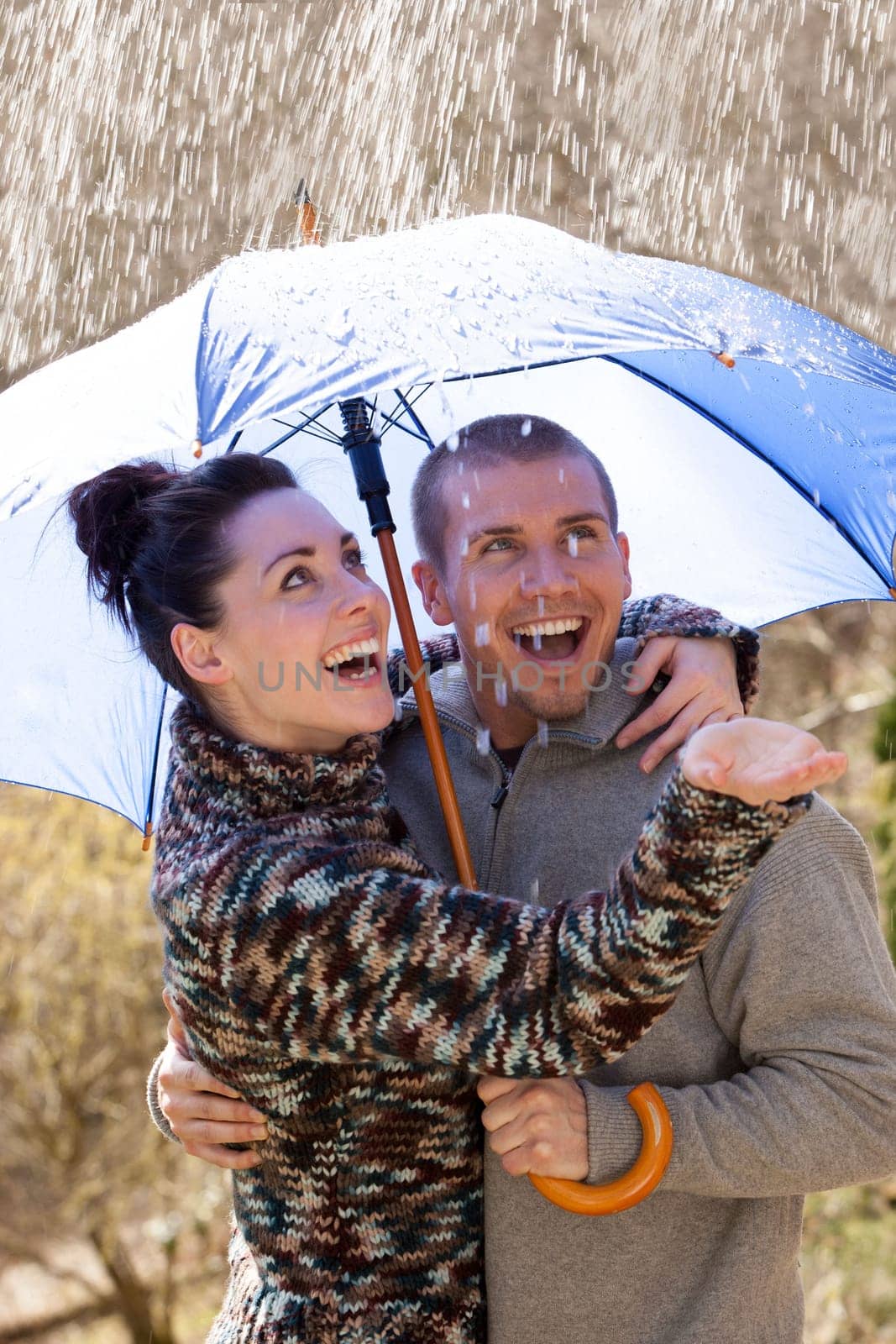 Young couple enjoying the rain under an umbrella
