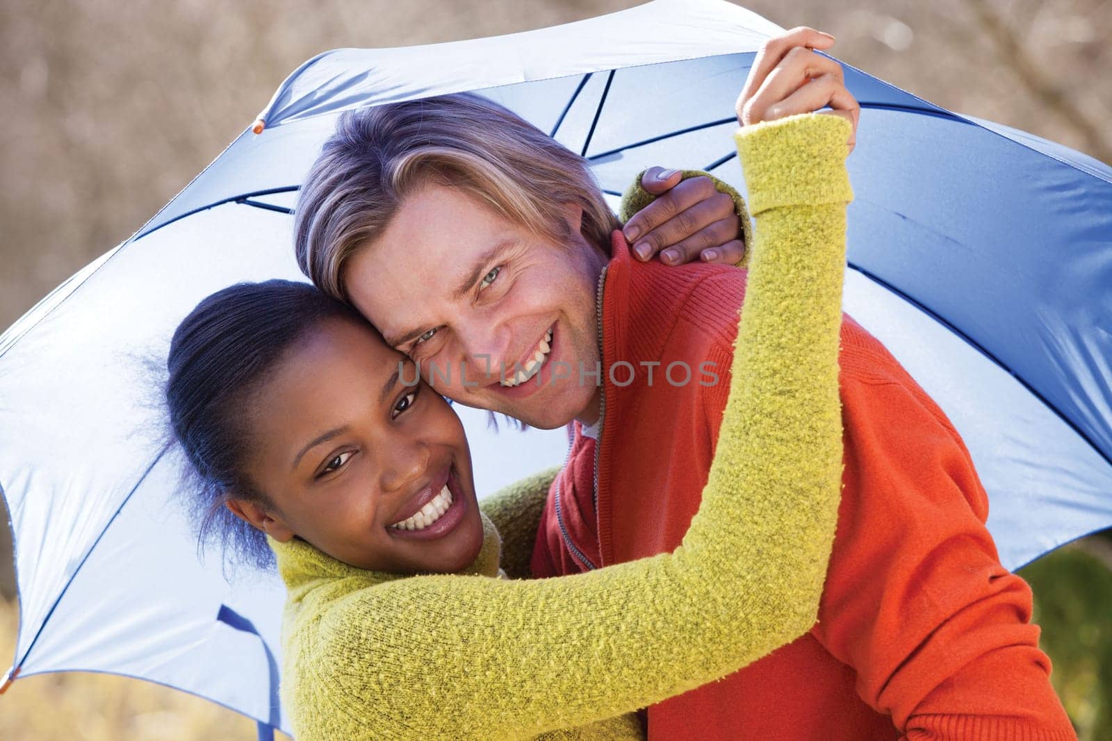 Young couple laughing in the rain under an umbrella